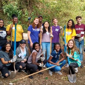Group of students hold rakes outdoors.