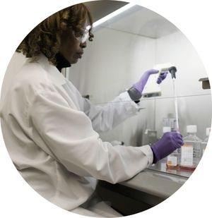 A woman in lab coat uses medical instrument.