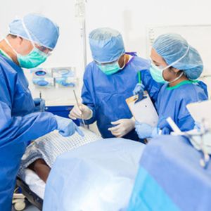 Three doctors discuss over cadaver