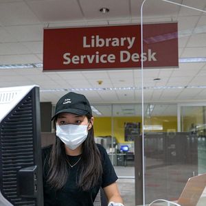 Student with hat sits at computer desk.