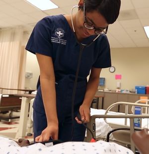 Nursing student tends to patient.