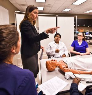 A professor demos on a mannequin for students.